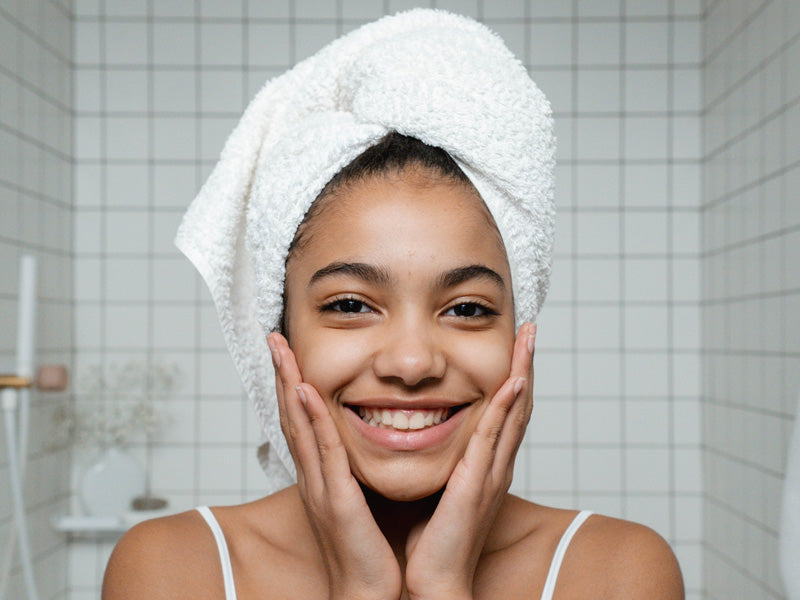 Smiling woman with a towel wrapped around her hair, glowing healthy skin