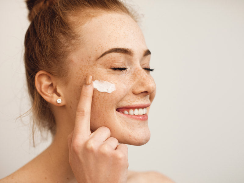 Woman applying a calming skincare product to her face