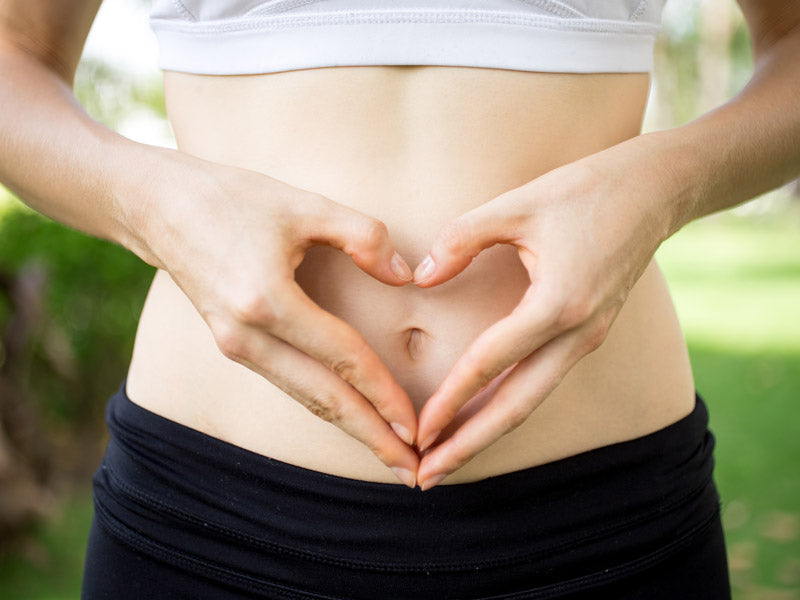 Close-up of hands shaping a heart over the stomach