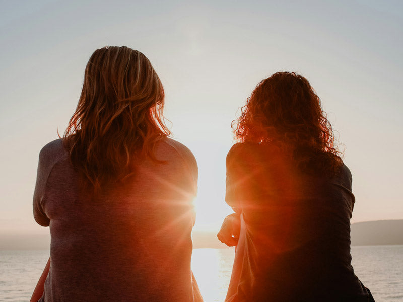 Two women looking out at the sunset together
