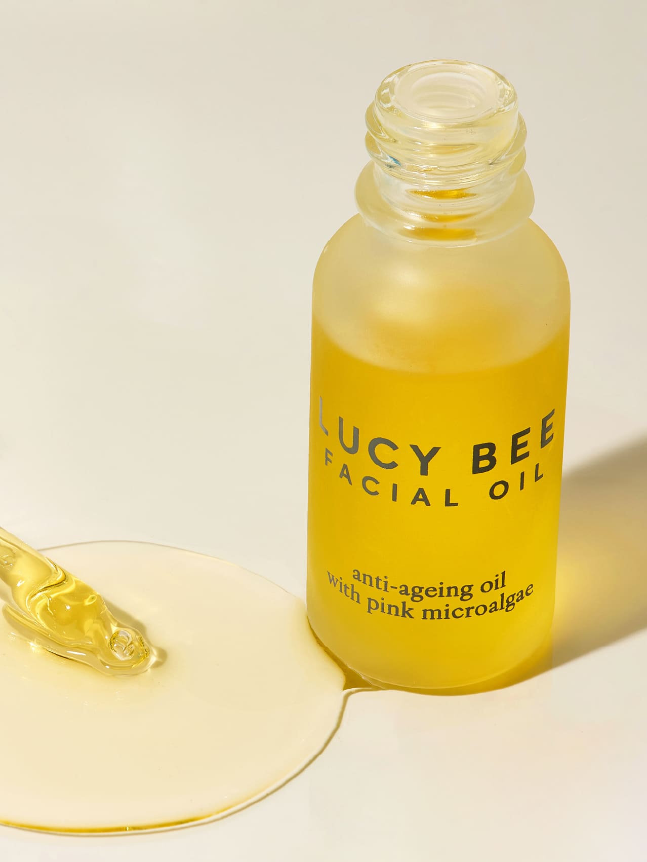 Bottle of Lucy Bee facial oil with a dropper on a light background