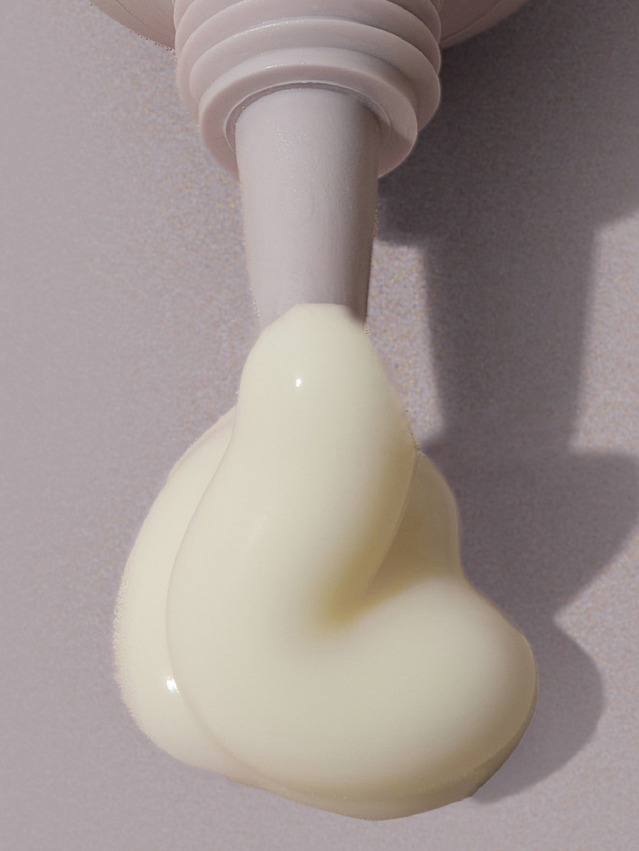 Close-up of a anti ageing eye serum being squeezed from a tube onto a gray background