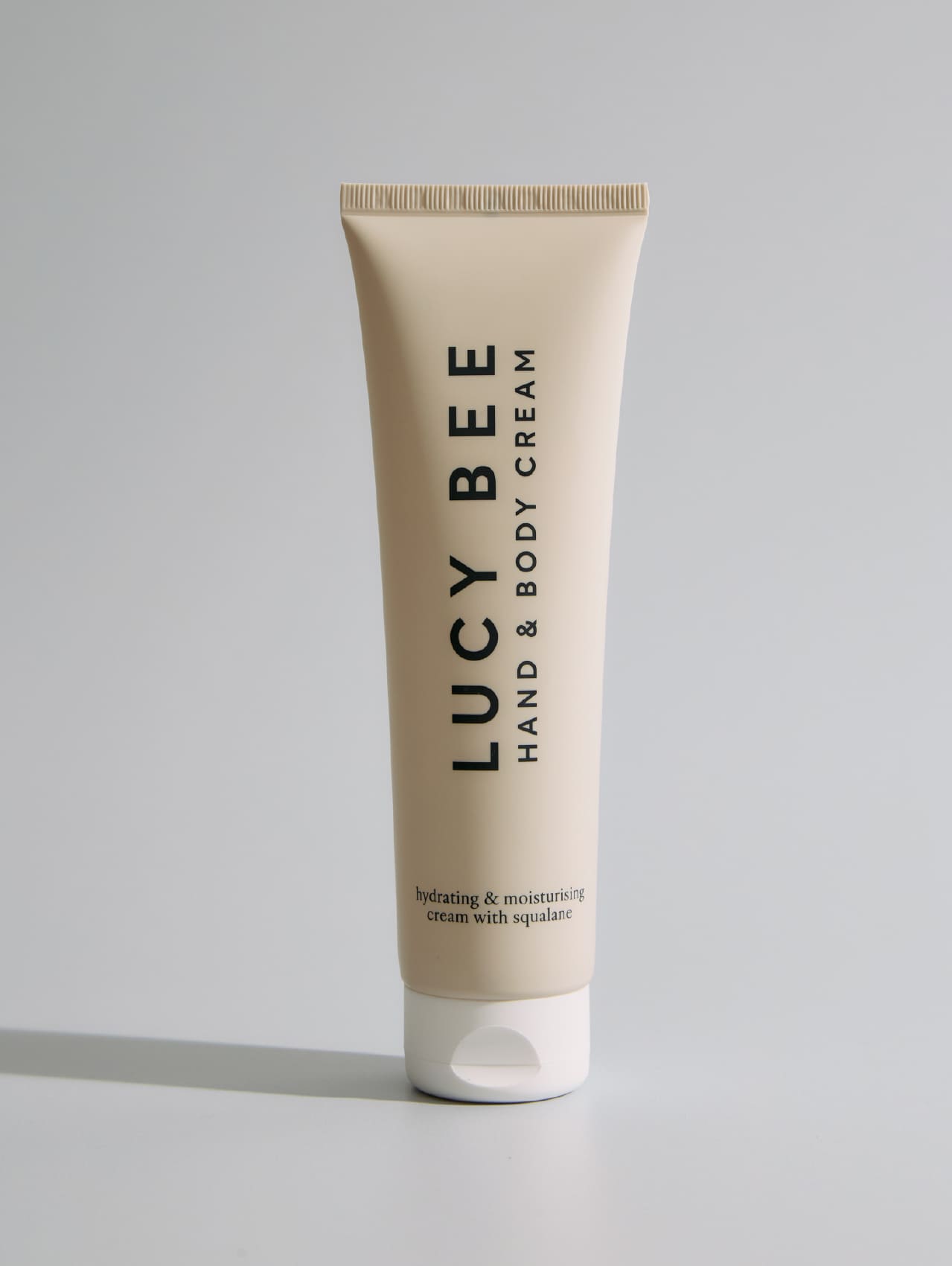 Tube of Lucy Bee hand and body cream on a gray background