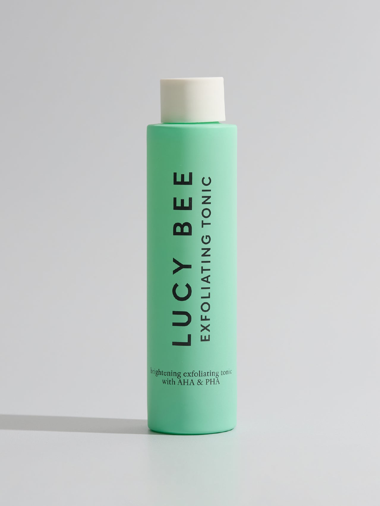 Green bottle of Lucy Bee Exfoliating Tonic on a white background