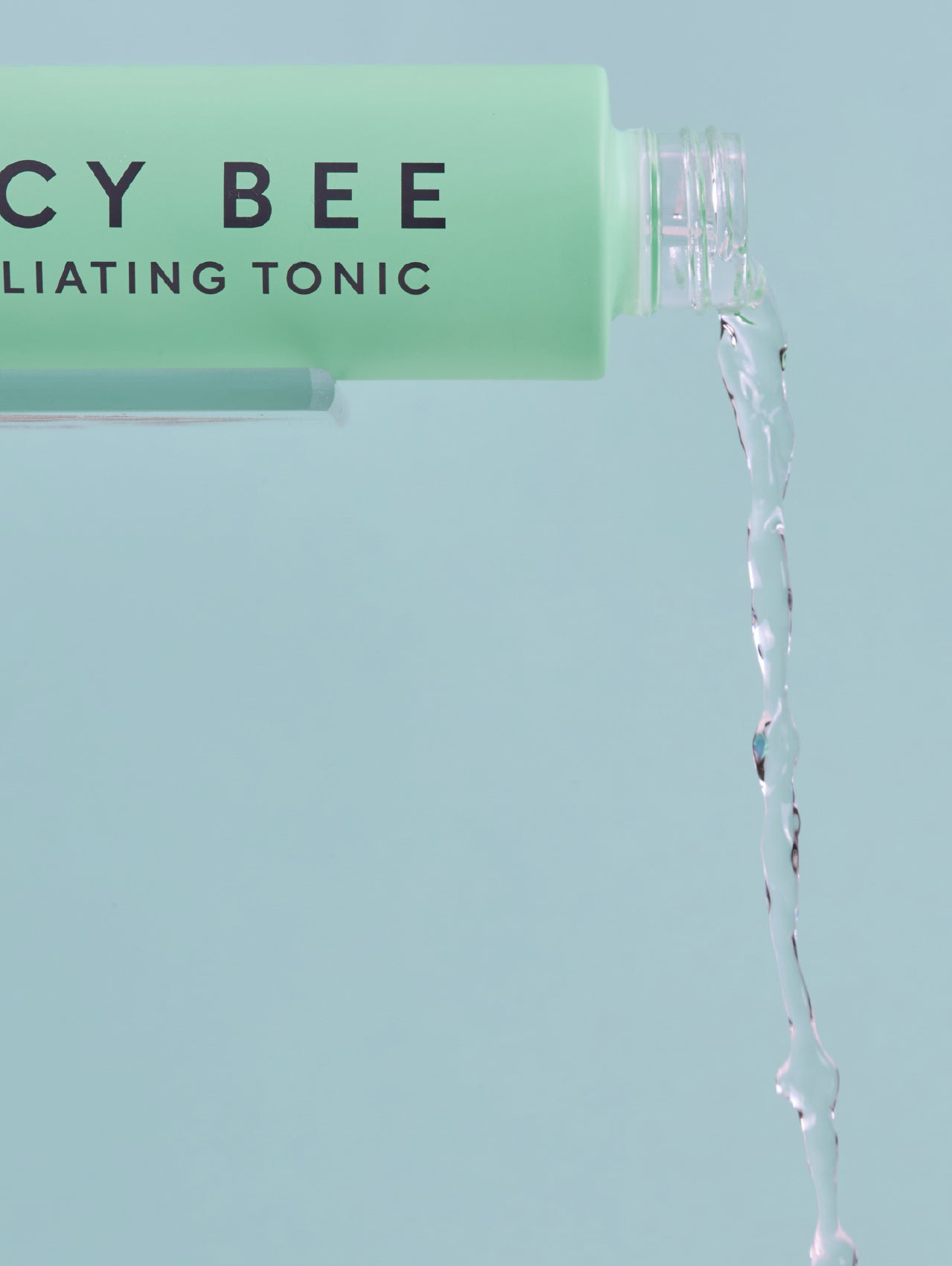 Lucy Bee exfoliating tonic being dispensed with a light blue background