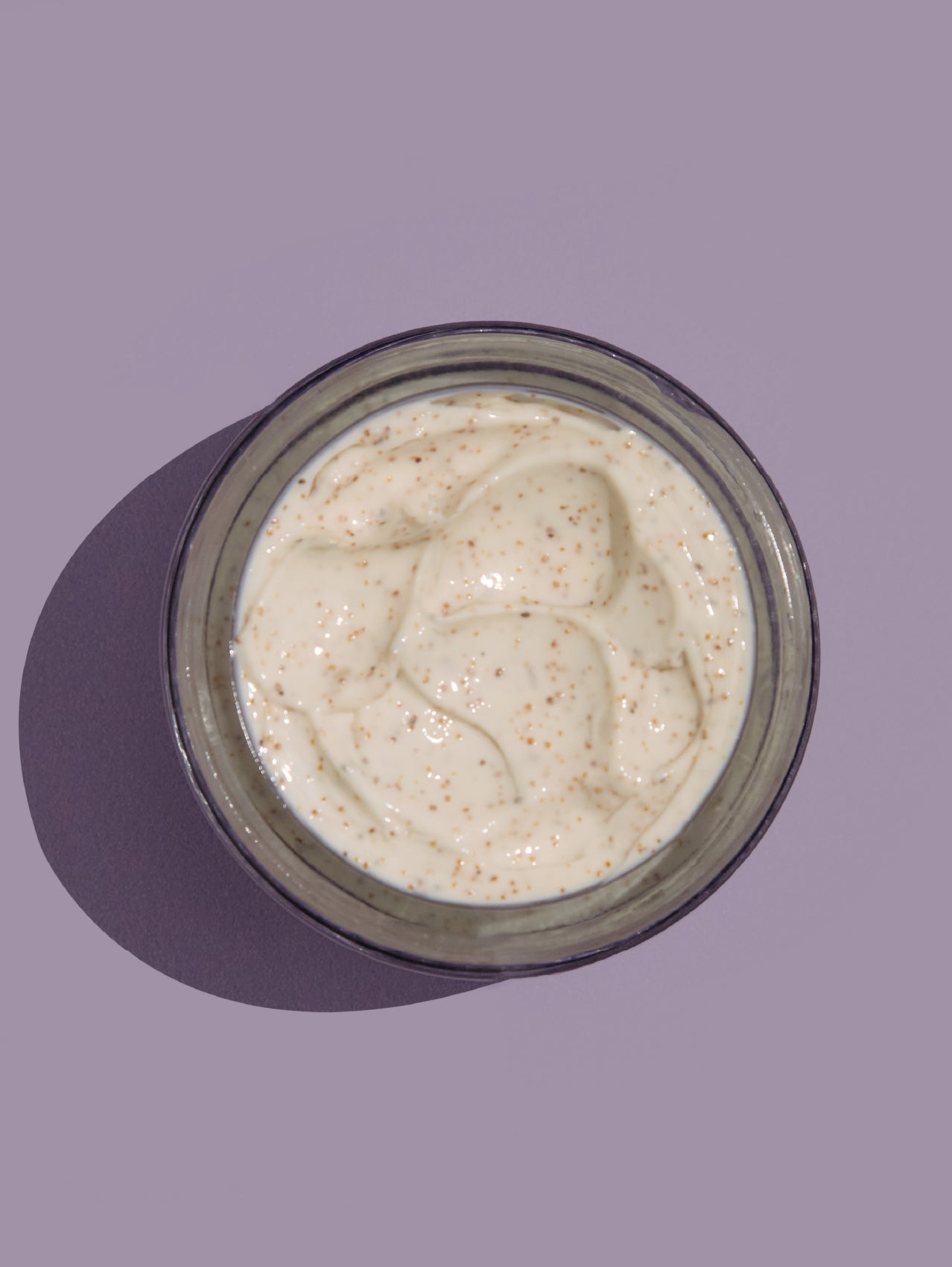 Jar of face scrub on a purple background