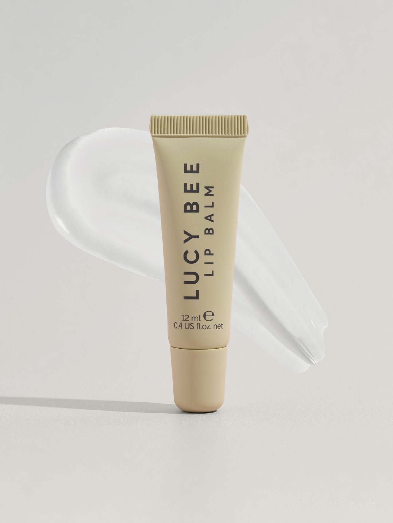 Lucy Bee lip balm tube on a light gray background