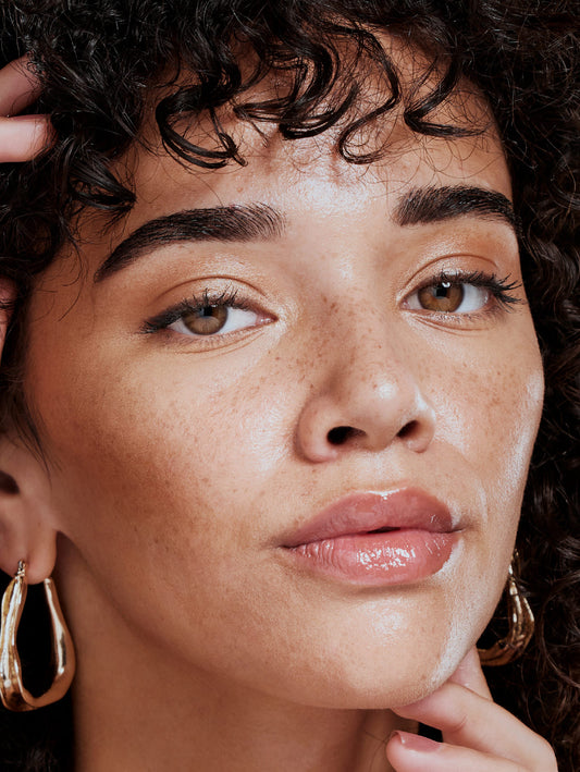 Close-up of a person with curly hair wearing gold hoop earrings.