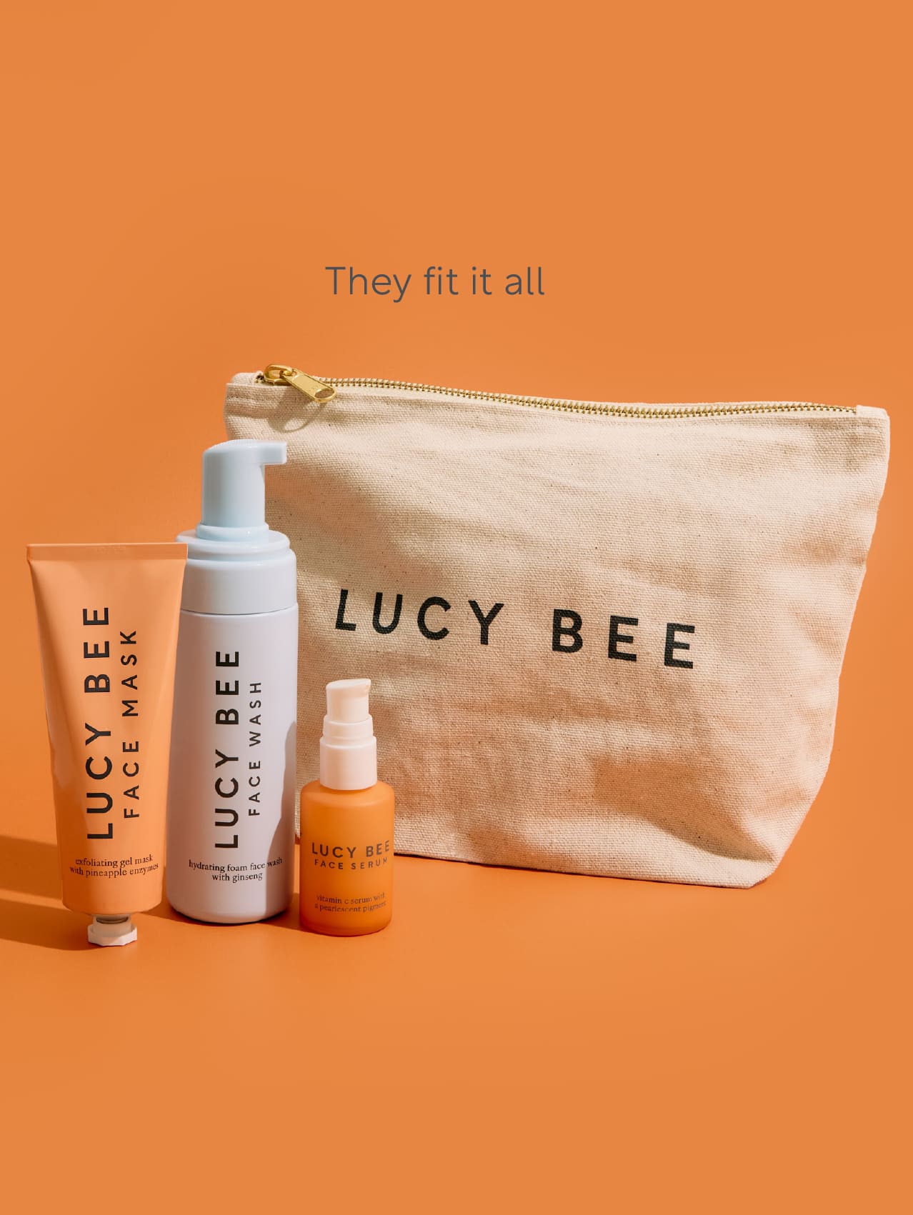 Lucy Bee skincare products including a pouch, face mask, and bottles on an orange background.