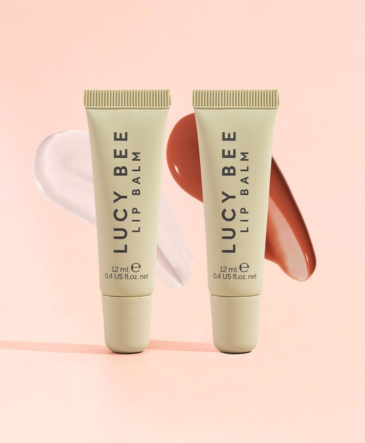 Two tubes of Lucy Bee lip balm on a pink background
