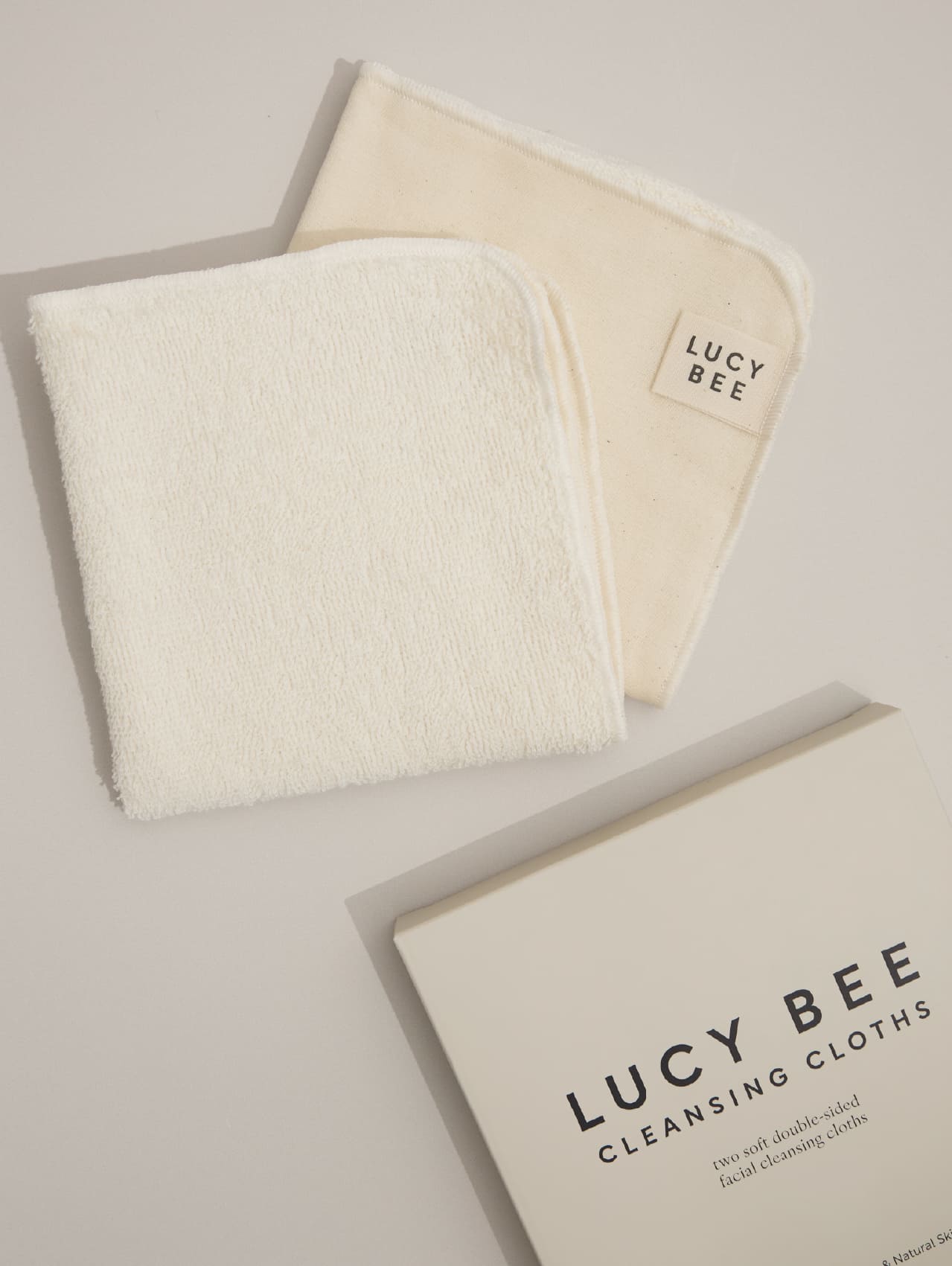 Two white Lucy Bee cleansing cloths and a box labeled