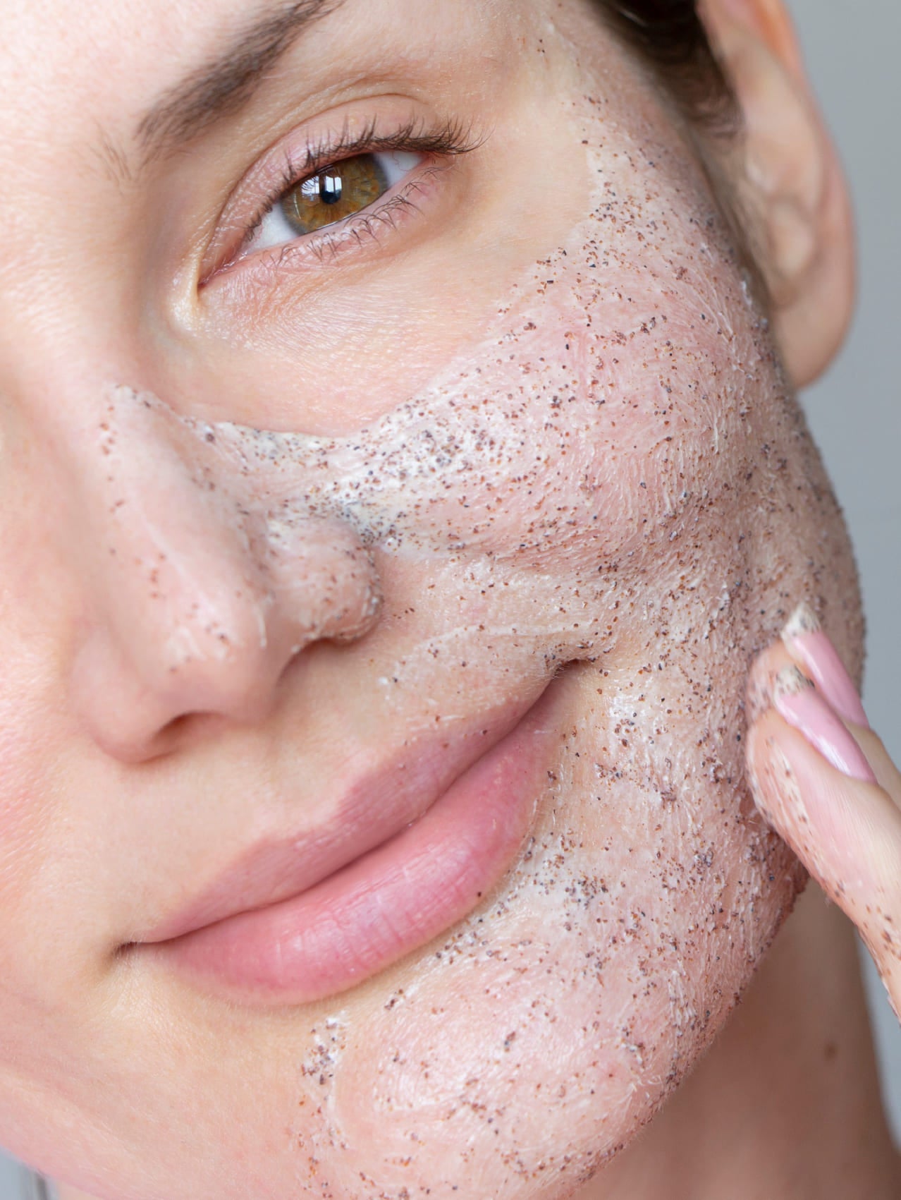 Close-up of a person applying Lucy Bee facial scrub to their skin.
