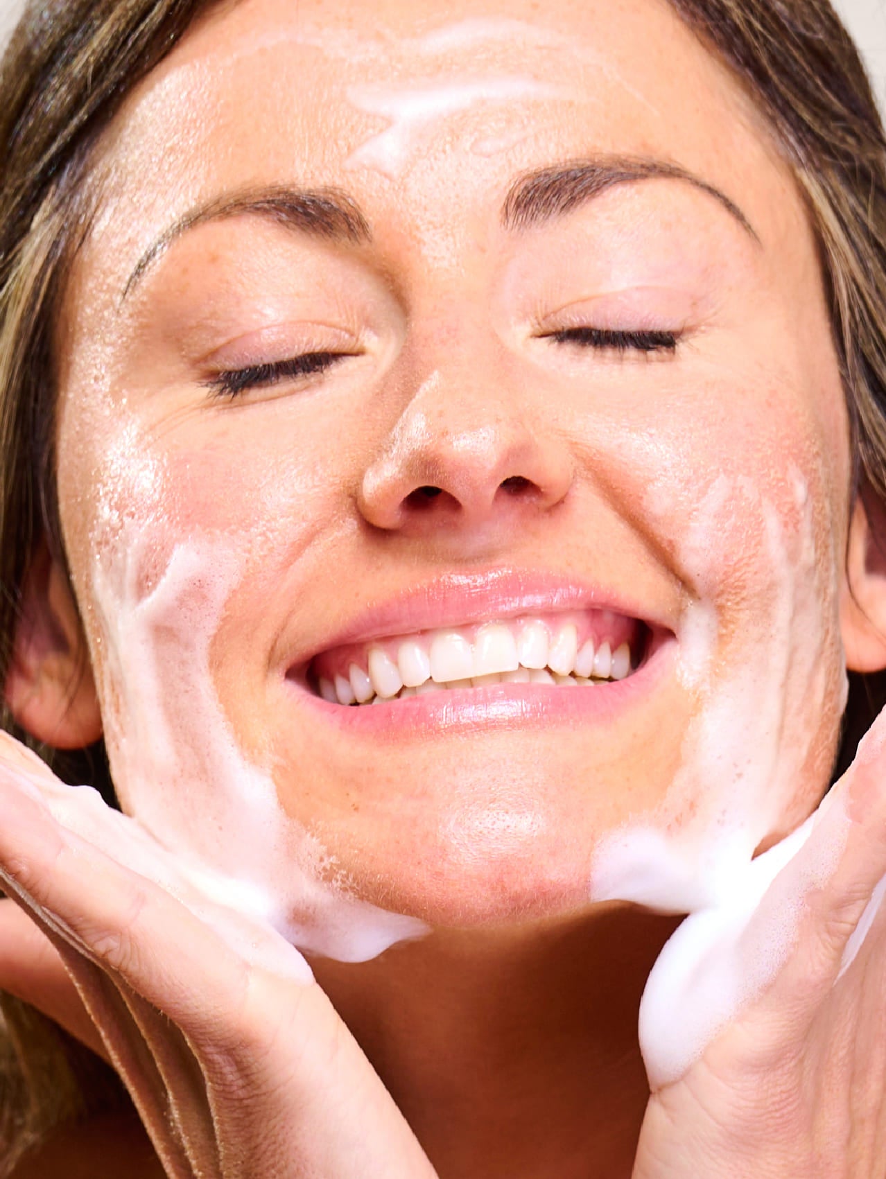 Woman applying face wash to her face with a close-up view