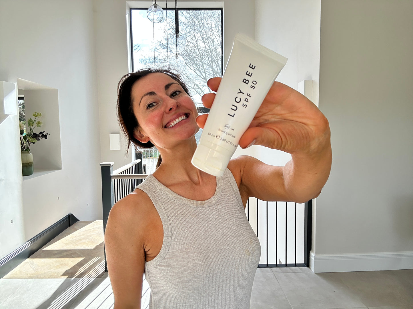 Person holding a bottle of LUCY BEE product with a modern indoor background