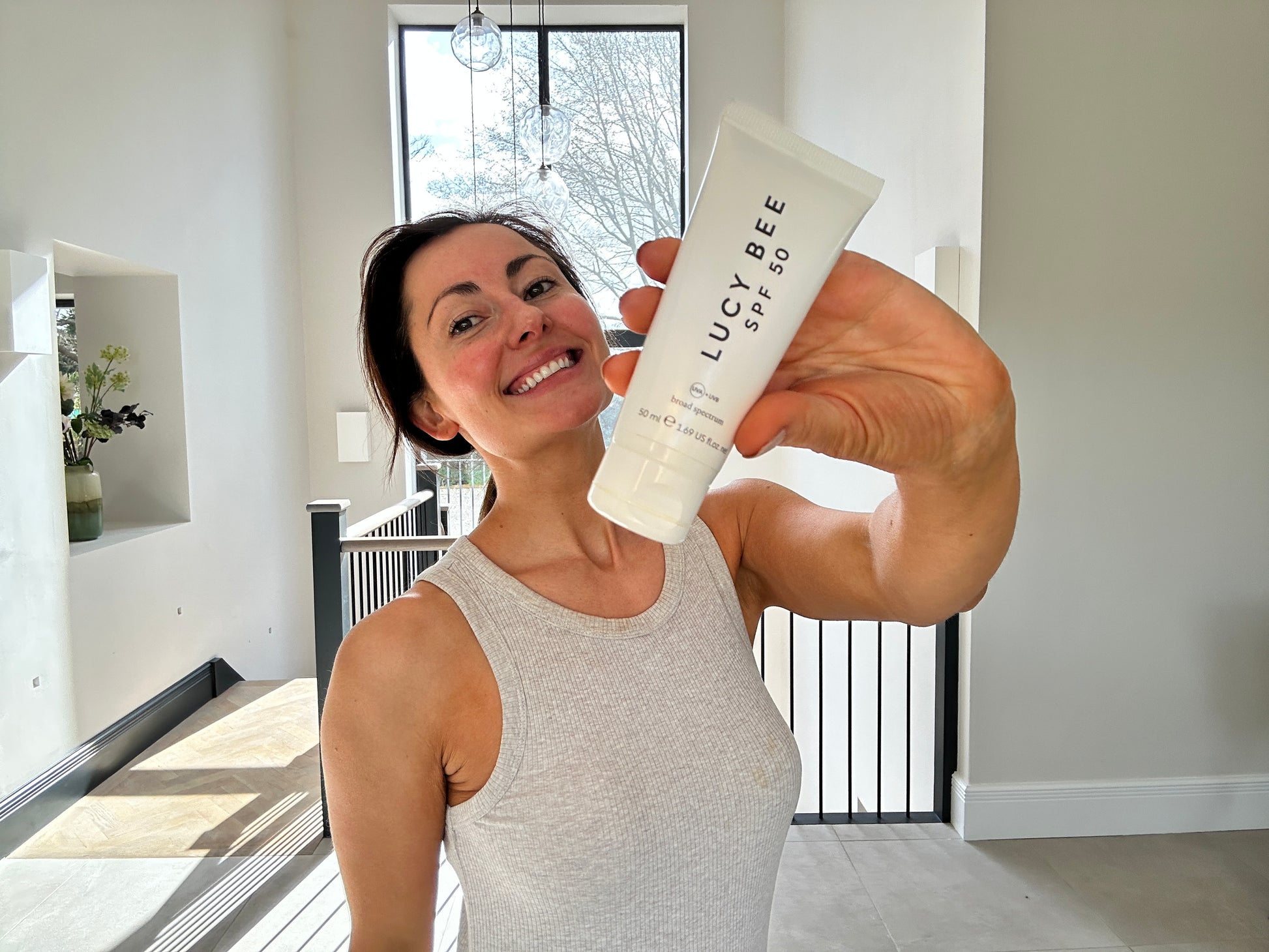 Person holding a bottle of LUCY BEE product with a modern indoor background