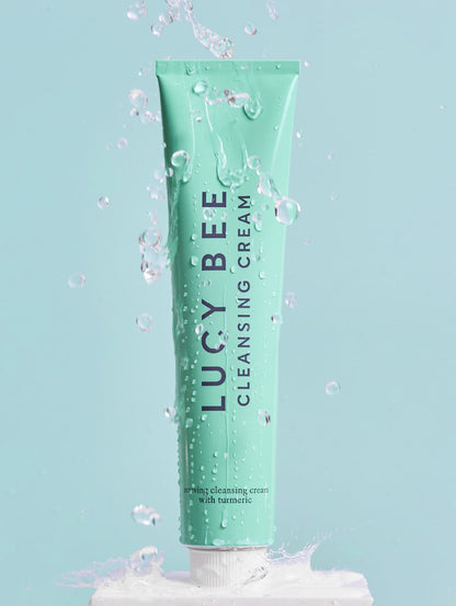 Tube of Lucy Bee cleansing cream with water droplets on a light blue background