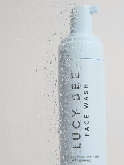 Lucy Bee natural face wash bottle with foam on a light gray background