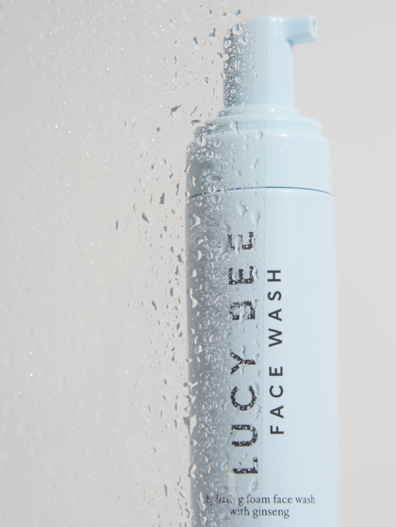 Lucy Bee Natural face wash bottle with foam on a light gray background