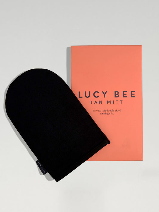 Black tan mitt and pink packaging with 'Lucy Bee' branding on a light gray background