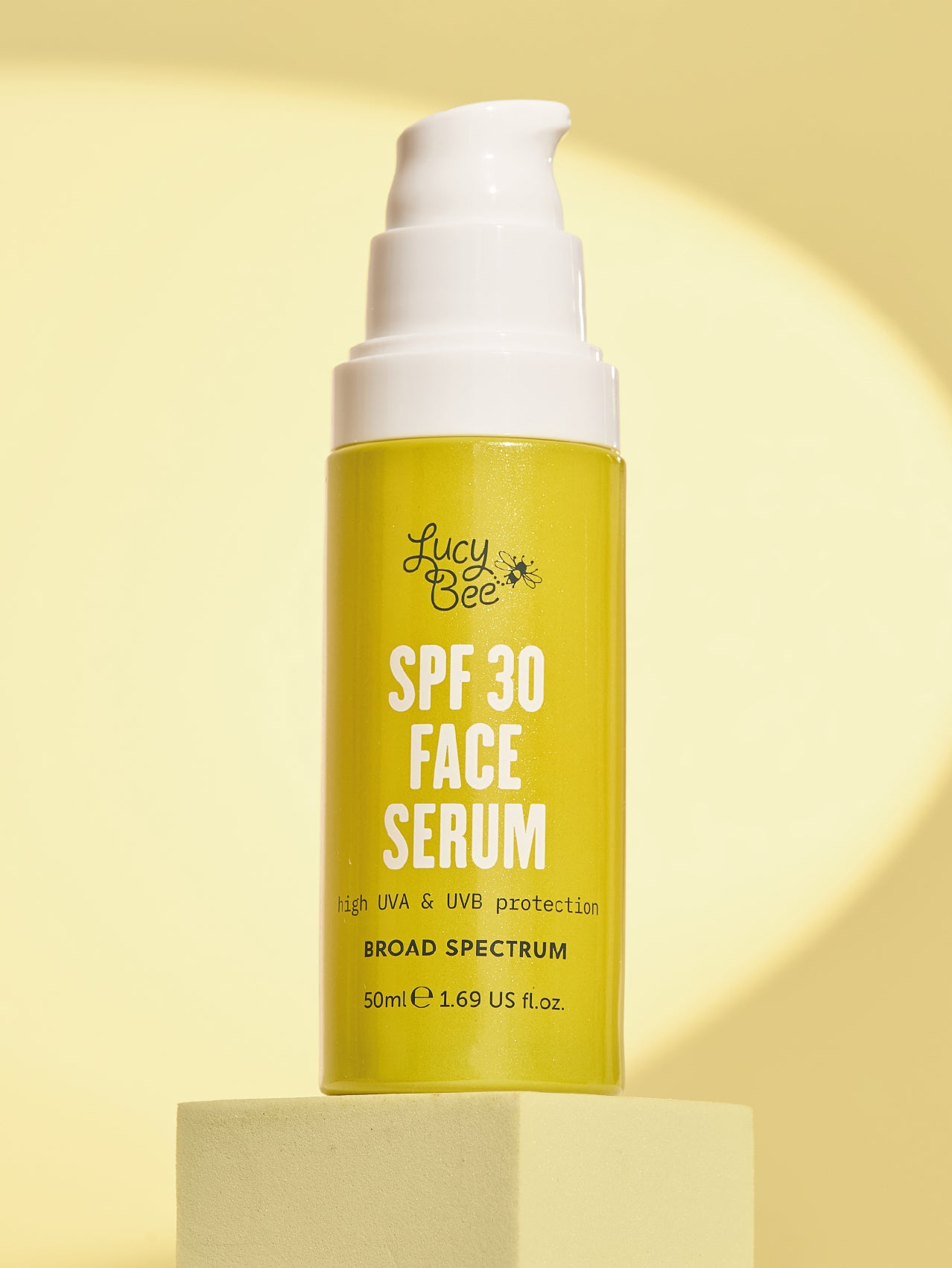 Yellow SPF 30 face serum bottle with white pump on a yellow background