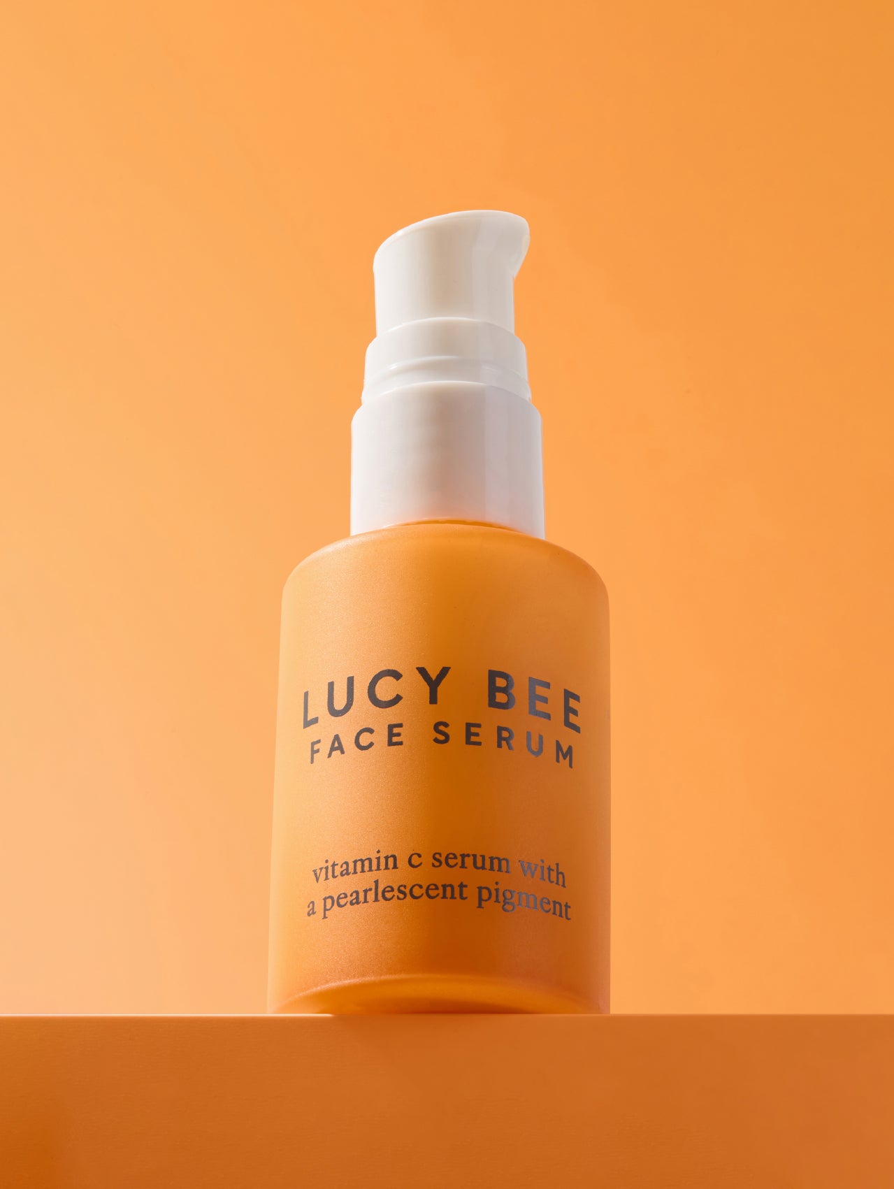 Lucy Bee face serum bottle on an orange background